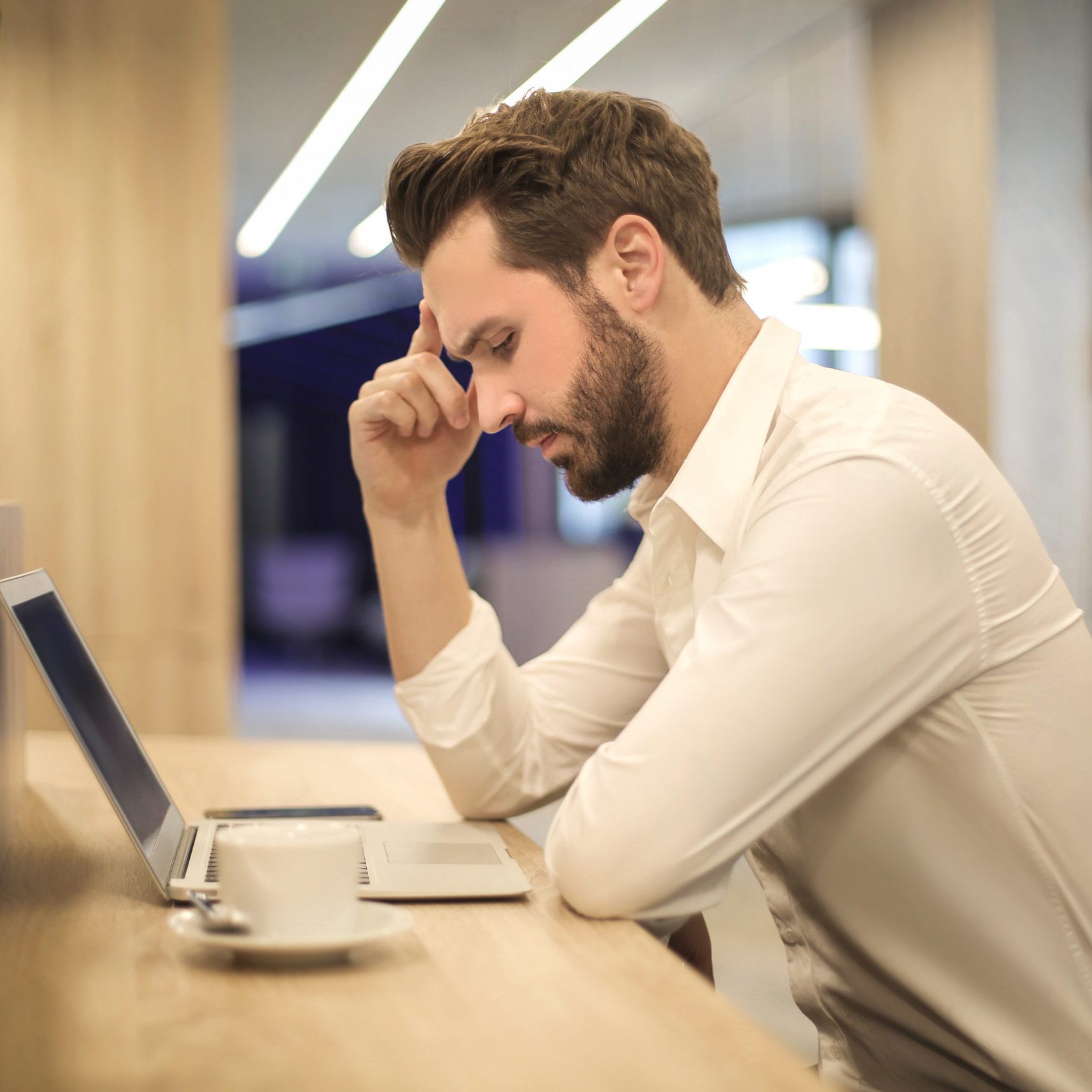 man-with-hand-on-temple-looking-at-laptop-842554